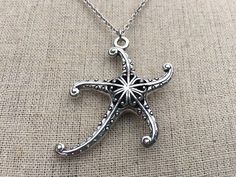 a silver necklace with an intricate starfish design hanging from it's center chain