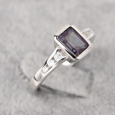 a ring with an amethorate stone and diamond accents on the sides, set in white gold