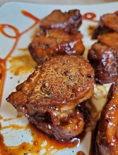 some meat is sitting on a white plate covered in gravy and sauces