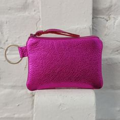 a pink purse hanging on a white brick wall