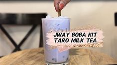 a person holding a straw in a tall glass filled with liquid that reads, jway boba kit taro milk tea