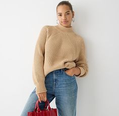 a woman is holding a red handbag and posing for the camera with her hands on her hips