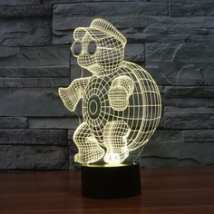 an illuminated teddy bear is sitting on top of a wooden table next to a brick wall