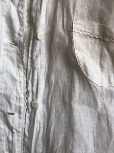 "Early workwear in white cotton. Mother of pearl buttons up the front, ties from the back. Shoulder seam to seam: 13.5\" Bust: 38\" Front length: 22.5\" Back length: 18\" Circa: 1910-1920 Condition: Good vintage condition. Normal wear. Some faint spots and a bit of discoloration throughout. One hole at the upper back. Hand-washed and ready to wear. Follow us on Instagram for the latest----> http://instagram.com/closetcasevintage @closetcasevintage Please contact us about any questions you may Vintage Linen Shirt With Button Closure, Vintage Linen Shirt With Buttons, White Shirt With Covered Buttons For Daywear, Vintage Linen Blouse With Buttons, Vintage White Shirt With Button Closure, White Cotton Blouse With Buttons, Cotton Blouse With Covered Buttons For Daywear, Vintage Button-up Blouse With Placket, Vintage White Linen Blouse