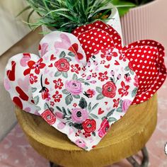 two heart shaped cushions sitting on top of a wooden table next to a potted plant