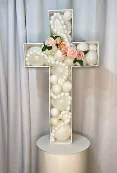 a cross made out of white balls and flowers