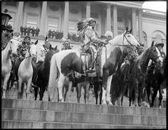 an old black and white photo of native americans on horses in front of a building