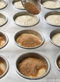 someone is sprinkling sugar on top of cupcakes in a muffin tin