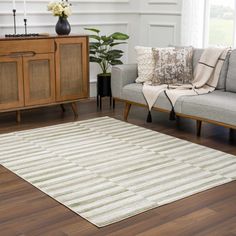 a living room filled with furniture and a rug on top of a hard wood floor