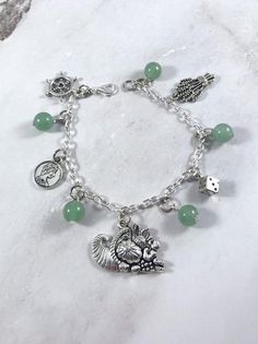 This fun, Tyche themed charm bracelet is the perfect accessory to showcase your love for the Greek Myths in a subtle way.Charms included:Ship’s WheelCoinCornucopiaDiceWheat5 aventurine gemstone beads are included between each charm.Comes in three sizes:Small: 6.5 inches (with extra rings at the end to expand up to 7.5 inches.)Standard: 7.5 inchesLarge: 8.5 inchesSecures with a lobster clasp. Bracelet and charms are made with zinc alloy and beads are natural gemstones. All materials are lead and Symbolic Vintage Charm Bracelet For Gift, Handmade Symbolic Charm Bracelet For Friendship, Greek Mythology Jewelry, Mythology Jewelry, Goddess Bracelet, Clasp Bracelet, Greek Myths, Themed Jewelry, Greek Goddess