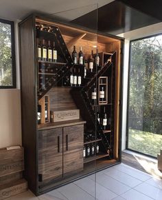 a wine cellar in the corner of a room with glass doors and shelves filled with bottles