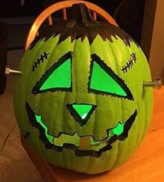 a carved pumpkin with green eyes on it's face sitting on top of a table