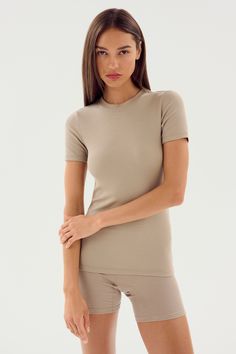 A woman with long brown hair, wearing the Louise Rib Short Sleeve in Latte by SPLITS59 along with matching shorts made from soft modal fabric, stands against a plain white background. Fitted Short Sleeve T-shirt For Loungewear, Fitted Crew Neck Activewear For Summer, Fitted Athleisure Tops For Everyday, Fitted Cropped T-shirt For Workout, Fitted Short Sleeve T-shirt For Yoga, Sporty Snug Fit Short Sleeve T-shirt, Fitted Seamless T-shirt For Loungewear, Fitted Basic T-shirt For Workout, Basic Fitted T-shirt For Workout