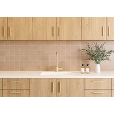 a kitchen with wooden cabinets and a white sink in front of a counter top next to a vase filled with flowers