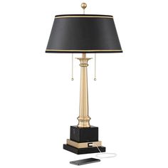 a black and gold lamp with a phone plugged into the charger next to it