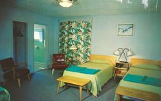 two beds in a room with blue walls and green bedding on the other side