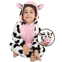 a young child wearing a cow costume sitting on the ground with his hands in his pockets