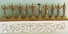 a group of gold figurines sitting on top of a white shelf next to a green wall