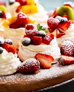 several desserts are arranged on a wooden platter with powdered sugar and fruit