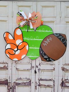 a football themed door hanger on the side of a white building with doors painted green and orange