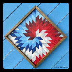 a red, white and blue quilt in a wooden frame on a wood plank wall