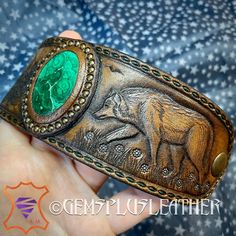 "\"Silver Shadow\" is a hand tooled leather cuff bracelet with carved fir forest, wolf and malachite lake. For those who's hearts are close to nature, Paganism, Wiccan, fantasy style. The cuff was made for a 7 1/2\" wrist. This exclusive piece wasn't made with special stamps or craftaids, just basic craft tools and my creativity. It's my design, I use my hands & imagination and add a piece of my soul into any item I make, so each of them is made with love. This particular bracelet was MADE TO OR Green Leather Jewelry Gift, Green Leather Jewelry As A Gift, Green Leather Jewelry For Gifts, Artisan Hand-tooled Jewelry Bracelet, Stamped Leather Cuff Bracelet Gift, Leather Bracelet Jewelry For Gifts, Green Leather Artisan Jewelry, Hand Tooled Bracelet Jewelry Gift, Custom Handmade Leather Bracelets