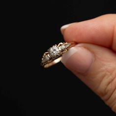 a woman's hand holding an engagement ring with three stones