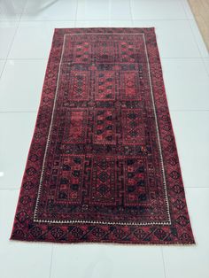 a large red rug on the floor in a room with tile floors and white walls