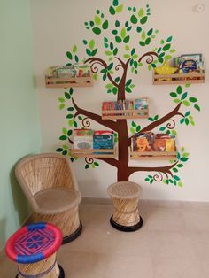 two wicker chairs sitting in front of a tree with books on it