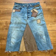 an old pair of jeans with holes and patches on them sitting on a wooden floor