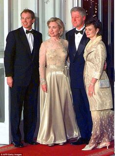 three men and two women in formal wear standing on a red carpet next to each other