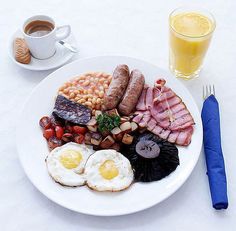 a white plate topped with breakfast foods next to a cup of coffee