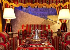 a living room filled with red and gold furniture next to two lamps on either side of the couch