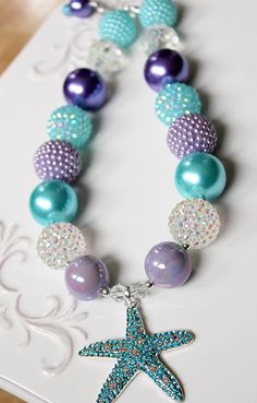 "This necklace features a beautiful rhinestone starfish pendant. Part of my \"Summer Nautical\" line, with a summery palette of aqua blue, purple and iridescent sparkle inspired by a mermaid at sea, it is the perfect accent for your photo shoot or outfit. To see more summer themed necklaces visit my summer section: https://www.etsy.com/shop/ChunkyStuffByLBB?section_id=17113232&ref=shopsection_leftnav_4 ✔ Necklaces come in child to adult sizes with a 2\" extender chain and jumbo lobster clasp Blue Beaded Necklace For Birthday, Blue Jewelry With Colorful Beads For Birthday, Blue Beaded Necklace For Birthday With Round Beads, Blue Necklaces With Starfish Charm And Round Beads, Blue Round Bead Necklaces For Birthdays, Blue Round Beads Necklaces For Birthday, Summer Necklaces, Pen Ideas, Purple Beads