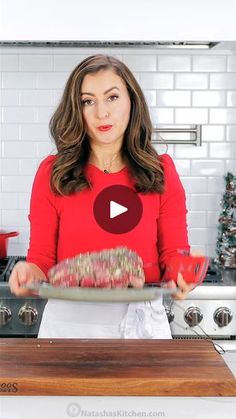 a woman in a red shirt is holding a pan with food on it