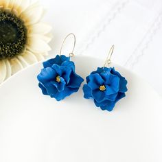 Elevate your style with our stunning Indigo Blue Earrings for women, perfect for adding a touch of elegance to any outfit. These Navy Blue Bridesmaid Earrings with a hint of gold are ideal for weddings or special occasions. Handcrafted with botanical-inspired designs, these dangle earrings feature delicate flowers sculpted from lightweight polymer clay, making them comfortable to wear all day long. Whether you're a plant mom or looking for a thoughtful gift, these hypoallergenic earrings with surgical steel hoops are ideal for sensitive ears. For extra versatility, there's a clip-on option available too. Shop now and treat yourself or a loved one to these unique and stylish botanical jewelry earrings. Since all items are handmade you may see slight variations in color or pattern from the p Navy Blue Bridesmaid, Navy Blue Bridesmaids, Clay Making, Bridesmaid Earrings Gold, Clip On Earring, Earrings Clay, Botanical Jewelry, Delicate Flowers, Blue Bridesmaids