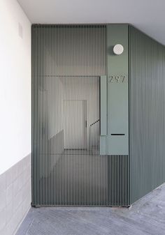 an empty room with a metal door and light fixture on the wall, next to a tiled floor