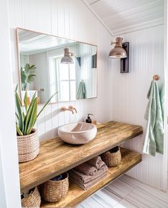 a bathroom with a sink, mirror and towels on the shelf in front of it