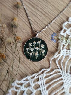 Vintage style hand embroidered pendant with tiny camomiles / daisies in a round pendant. Adorn yourself with the beauty of nature with this exquisite hand embroidered necklace featuring tiny camomiles delicately stitched on a lush green background. Each petal and leaf is meticulously crafted by hand, creating a stunningly detailed piece of floral jewelry. This necklace is not just an accessory, it's a wearable work of art that celebrates the intricacy of nature and the artistry of hand embroidery. Made with love and attention to detail, it's a perfect statement piece for nature lovers and those who appreciate fine craftsmanship. Elevate your style with this unique necklace that captures the essence of springtime. Whether you're dressing up for a special occasion or adding a touch of nature Embroidery Pendants, Hand Embroidered Pendant, Daisy Vintage, Embroidery Pendant, Hand Embroidered Necklace, Embroidered Pendant, Embroidered Necklace, Floral Jewelry, Floral Jewellery