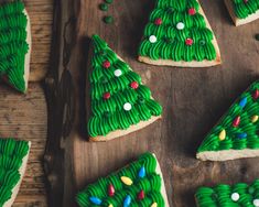 decorated cookies with green icing and christmas trees on them are arranged on a wooden board