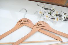 two wooden hangers with the names of bride and groom on them, next to flowers