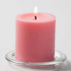 a pink candle is sitting on a clear plate