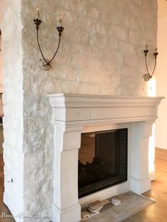 a white fireplace with two sconces on the wall