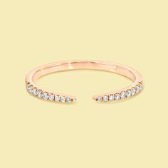 an open rose gold ring with white diamonds on top and side stones in the middle