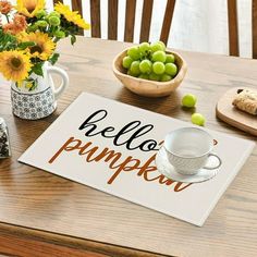 there is a place mat with the words hello pumpkin on it next to coffee cups and flowers