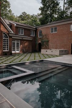 an outdoor swimming pool in front of a brick house