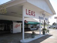 an empty gas station with cars parked on the side of the road in front of it