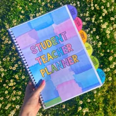 a person holding a notebook with the words student teacher planner on it in front of some flowers