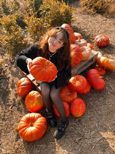 a woman sitting on top of a pile of pumpkins