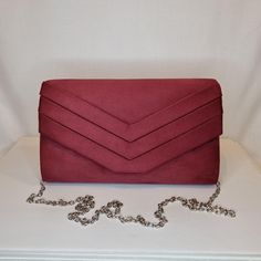 Womens burgundy red all-over faux suede evening clutch bag with front detailing and magnet front closing clasp Can be used with or without long shoulder chain (included) size approx- H 15cm x W 24cm Optional Dust Bag: White lightweight soft polyester portable travel dust bag pouch, suitable for protecting items from dust, dirt, hairs and scratches when not in use size approx- L 47cm x W 31.5cm Material: 100% polyester Please note, there is a cut in the top corner of the bag. In order to reveal t Burgundy Rectangular Clutch For Evening, Burgundy Rectangular Evening Clutch, Rectangular Burgundy Evening Clutch, Burgundy Clutch Bag For Party, Chic Burgundy Clutch For Party, Rectangular Burgundy Clutch For Party, Chic Burgundy Evening Bag For Party, Chic Burgundy Clutch Evening Bag, Chic Burgundy Clutch For Formal Occasions